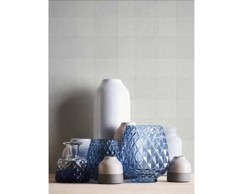 Verschiedene Vasen auf einem Tisch vor einer gemusterten Tapete