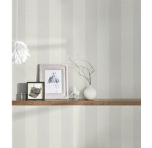 Photo d''intérieur d''une pièce avec du papier peint rayé, décorée d''une étagère en bois, de cadres photo et d''une lampe