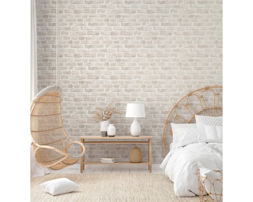 Helles Schlafzimmer mit Backsteintapete, Rattansessel und Bett