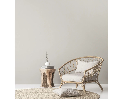 Intérieur lumineux avec fauteuil en rotin, tapis rond et table d''appoint en bois.