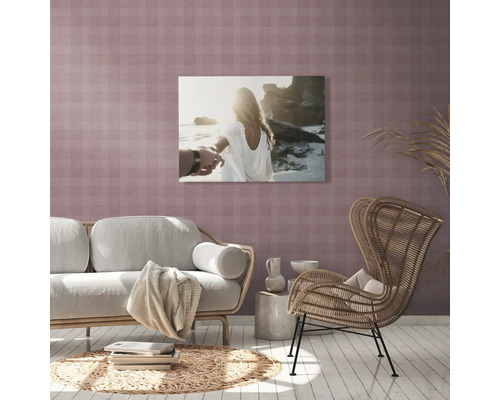 Wohnzimmer mit Sofa, Sessel, Beistelltisch, Teppich und einem Wandbild mit einem Paar am Strand.