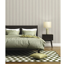Chambre avec lit, lampe de chevet, papier peint rayé et tapis à motifs zigzag