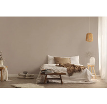Helles Schlafzimmer mit Bett, Holzhocker und Rattanhängelampe für eine freundliche Atmosphäre.