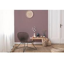 Salon avec fauteuil en rotin, table en bois et décorations sur un tapis