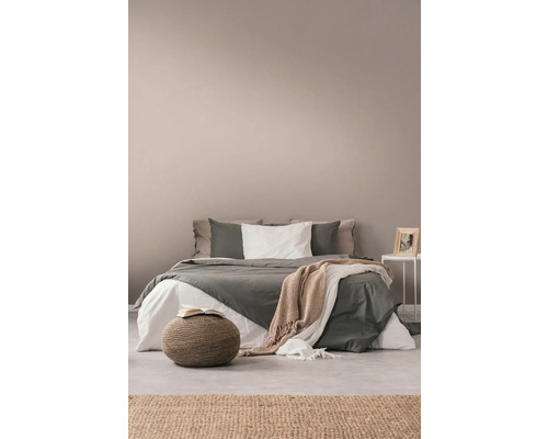 Schlafzimmer mit Bett, Beistelltisch, Teppich und Sitzhocker