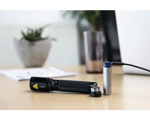 Lampe de poche à batterie avec batterie et câble de charge sur une table