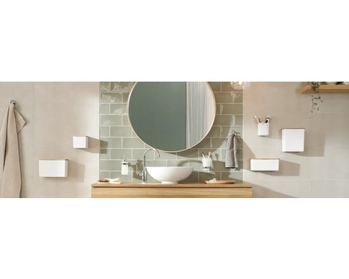 Helles Badezimmer mit rundem Spiegel, Waschtisch und Badaccessoires.