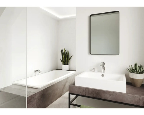 Badezimmer mit Badewanne, Waschbecken, Spiegel und Pflanzen für eine helle und freundliche Atmosphäre.