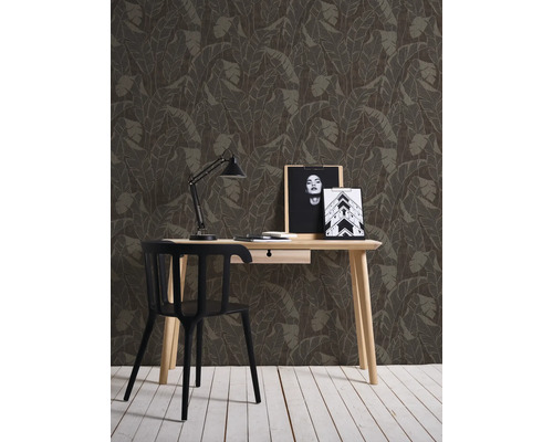 Mur décoratif avec papier peint à feuilles derrière un bureau avec une chaise.