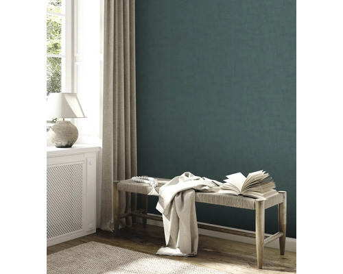 Intérieur avec mur vert foncé, banc, livre et textiles.