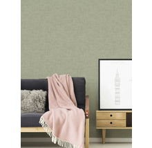 Scène d''intérieur avec un papier peint structuré, un canapé avec une couverture et des coussins, ainsi qu''un petit meuble avec une image de Londres
