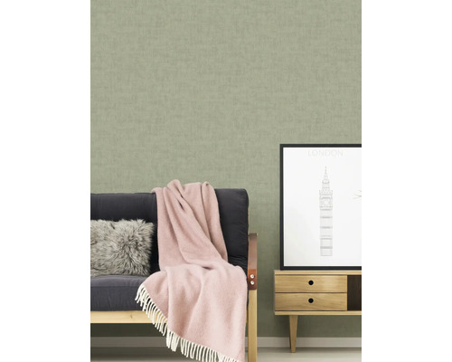 Scène d''intérieur avec un papier peint structuré, un canapé avec une couverture et des coussins, ainsi qu''un petit meuble avec une image de Londres