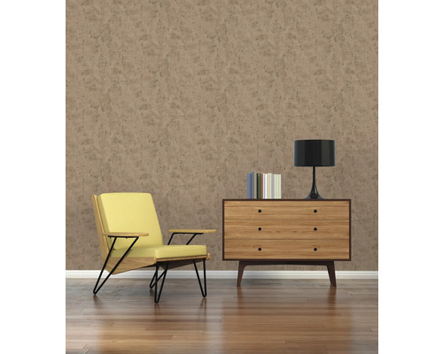 Salon avec fauteuil, commode, lampe et livres devant un mur marron