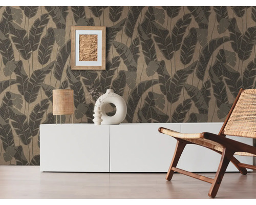 Salon avec papier peint à motifs de feuilles, buffet, lampe de table, cadre photo, objets de décoration et chaise en bois