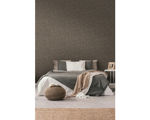 Chambre à coucher avec papier peint à motifs, lit, tabouret et tapis pour une ambiance chaleureuse.