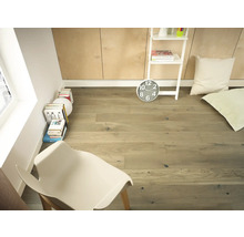 Pièce claire avec plancher en bois, étagère échelle, horloge, coussins et chaise.