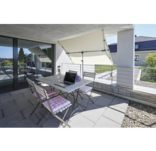 Balcon avec table pliante, chaises pliantes, parasol, ordinateur portable et bouteille de boisson