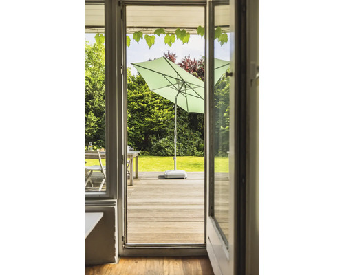 Vue à travers une porte ouverte sur une terrasse avec parasol et mobilier de jardin