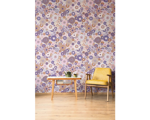 Une pièce avec un papier peint à motifs, un fauteuil et une table avec une théière.