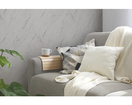 Salon avec canapé gris, coussins, couverture et papier peint mural imitation marbre