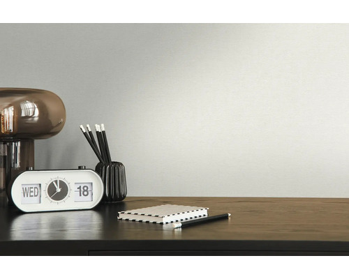 Nahaufnahme eines Schreibtisches mit Lampe, Uhr, Stiften und Notizbuch.