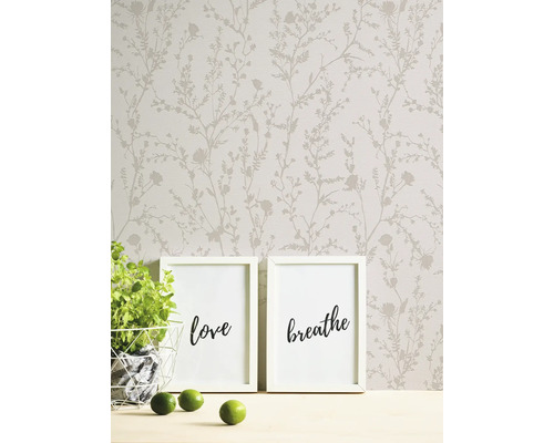 Scène avec papier peint floral, deux cadres, une plante et des citrons verts