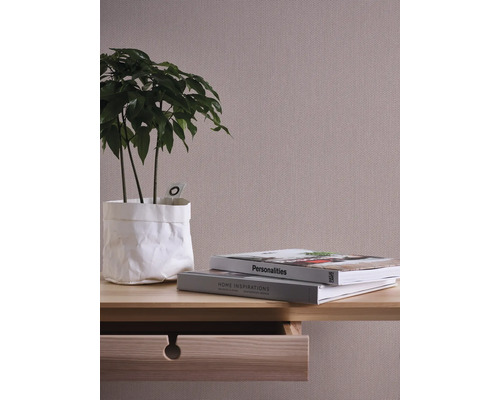 Gros plan d''un mur avec du papier peint textile, une table en bois avec tiroir, une plante d''intérieur et deux livres.