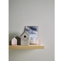 Maisons décoratives en béton et en bois sur une étagère avec une image en arrière-plan.