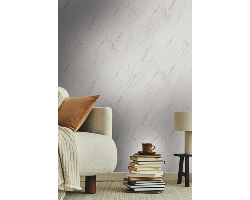 Salon avec papier peint à motifs, canapé, livres, lampe de table et tapis pour une ambiance cosy