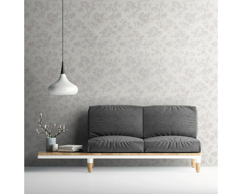 Aménagement avec canapé devant un papier peint à motif floral.
