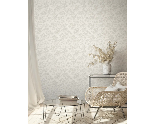 Salon avec papier peint à motifs floraux, fauteuil en rotin et table basse