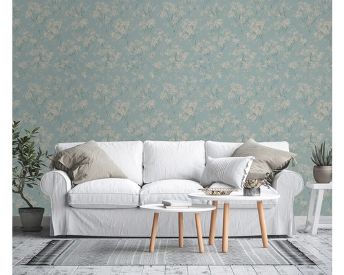 Wohnzimmer mit floral gemusterter Tapete, weißem Sofa und Couchtischen.