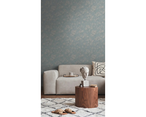 Wohnzimmer mit Sofa, Holztisch, Teppich und floral gemusterter Tapete