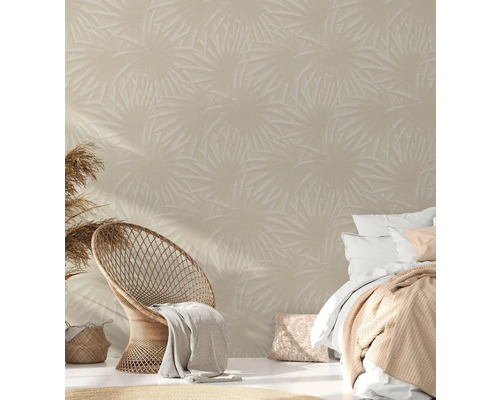 Wohnszene mit tropischer Blättertapete, Rattansessel und Bett für ein helles und geräumiges Ambiente.