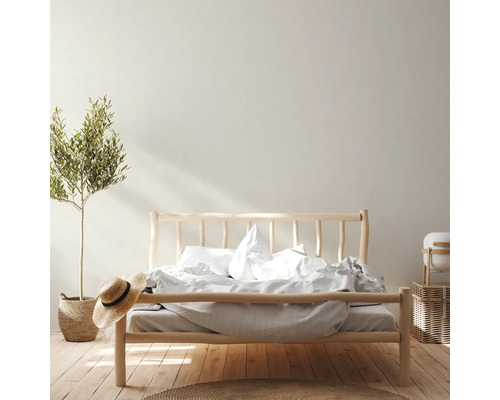 Helles Schlafzimmer mit Holzbett, Pflanze im Korb und Strohhut für eine freundliche Atmosphäre.