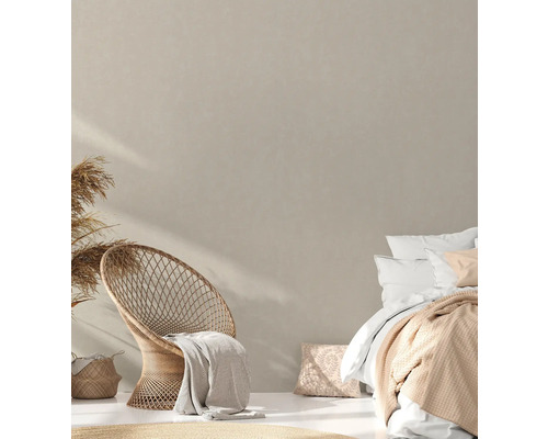 Chambre claire avec fauteuil en rotin, lit et éléments décoratifs pour une ambiance chaleureuse.