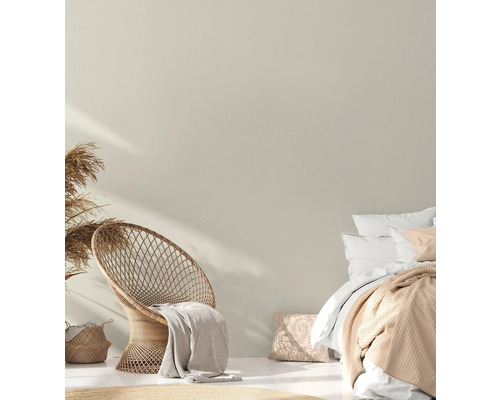 Hell gestalteter Schlafbereich mit Rattan-Stuhl und Doppelbett.