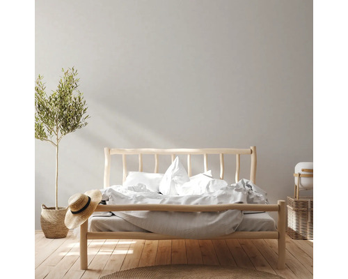 Schlafzimmer mit Holzbett, Pflanze und Accessoires für eine helle und freundliche Atmosphäre.