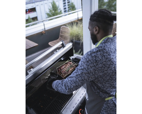 Mann bereitet Braten auf Grill im Freien zu