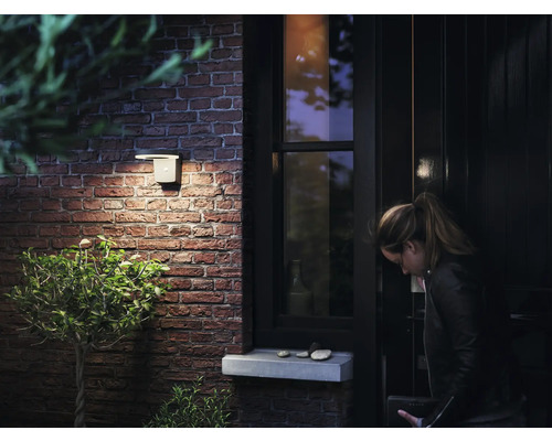 Un applique d''extérieur éclaire une entrée de maison avec un mur de briques