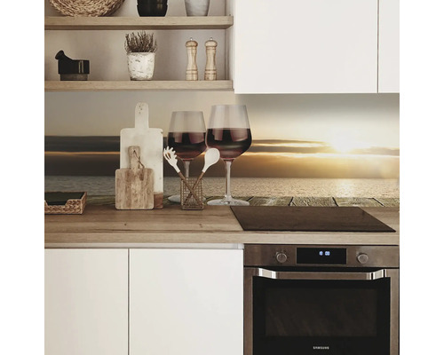 Scène de cuisine avec deux verres à vin, des planches à découper et des ustensiles de cuisine sur un plan de travail devant un fond de cuisine avec un motif de plage.