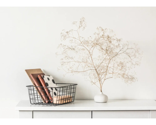 Dekorative Aufbewahrungskörbe mit Büchern und Vase mit Trockenblumen auf weisser Kommode