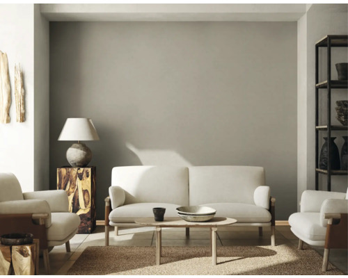 Wohnzimmer mit Sofa, Sesseln, Tisch, Lampe und Regal.