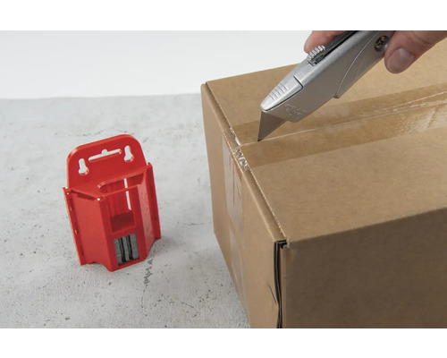 Un cutter ouvre un carton à côté d''un magasin de lames rouge.