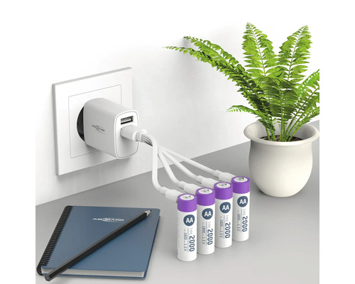 Chargeur avec quatre piles AA, un bloc-notes et un stylo sur une table
