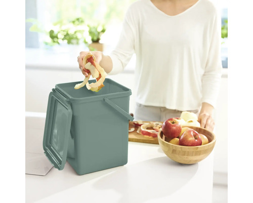 Frau wirft Apfelreste in einen Komposteimer in der Küche.