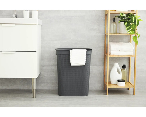 Salle de bain avec un panier à linge gris avec couvercle, un meuble-lavabo blanc et une étagère en bois