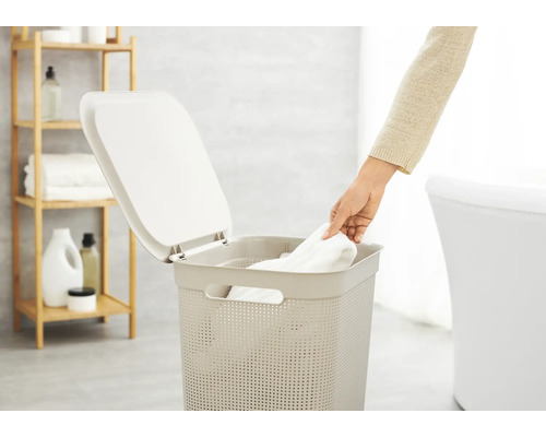 Panier à linge avec couvercle dans une salle de bain avec une personne y déposant une serviette.