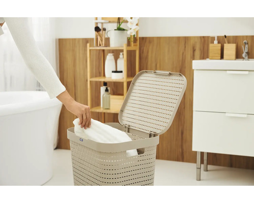 Une personne met du linge dans un panier à linge dans une salle de bains