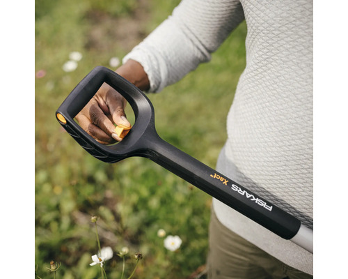 Gros plan d''une personne tenant une bêche Fiskars pour travailler dans le jardin.